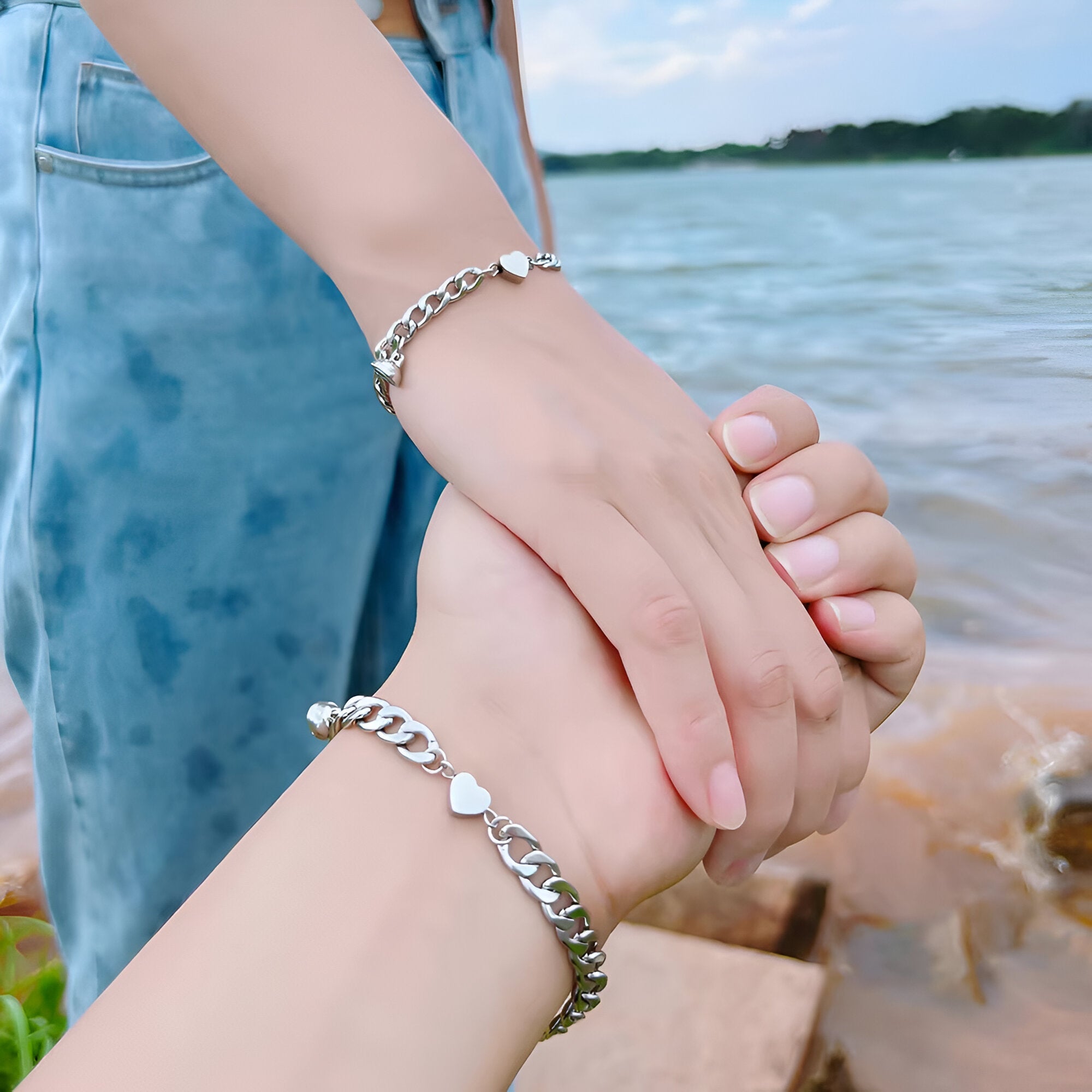 Duo de bracelets en acier inoxydable argenté avec petits cœurs, style chaîne épaisse, unisexe, porté au bord de l'eau.