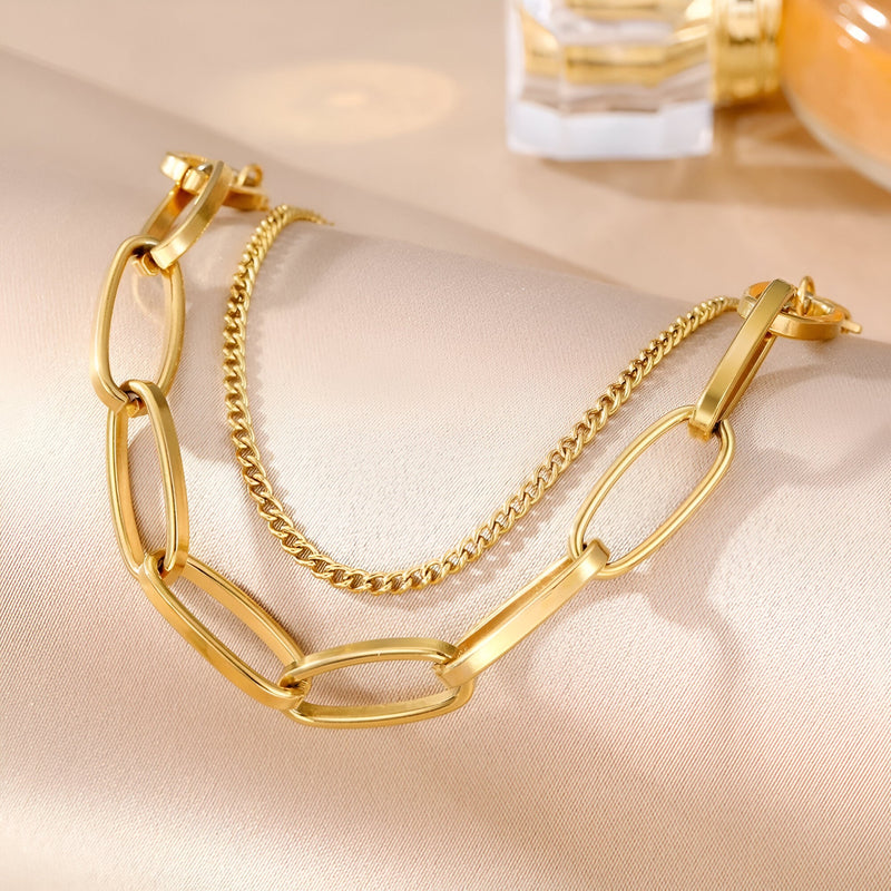 Duo de bracelets dorés en acier inoxydable, un à maillons larges, l'autre à chaîne fine et torsadée.