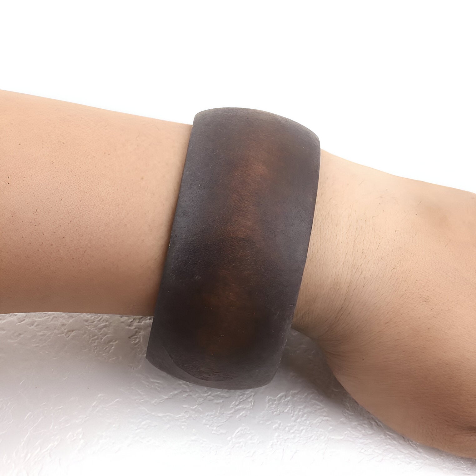Bracelet large en bois marron foncé à surface lisse et finition naturelle porté au poignet.