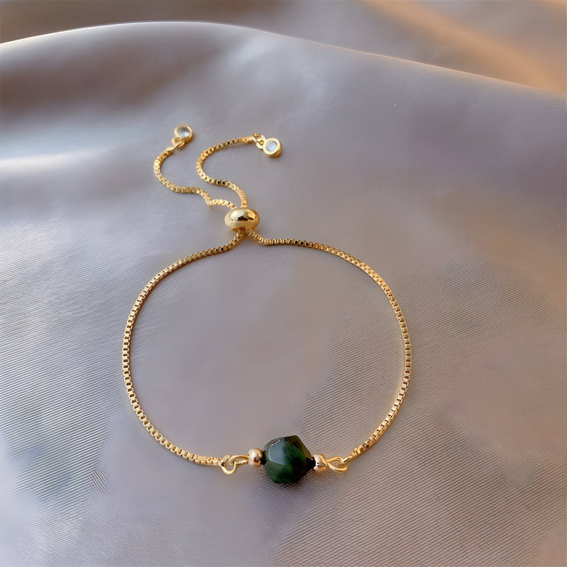 Bracelet fin doré avec perle œil de tigre verte facettée scintillante, fermoir coulissant.