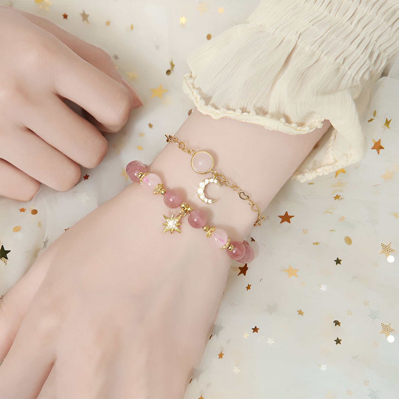 Duo de bracelets roses en pierres de cristal avec breloques étoile dorée et lune argentée attachés au poignet.