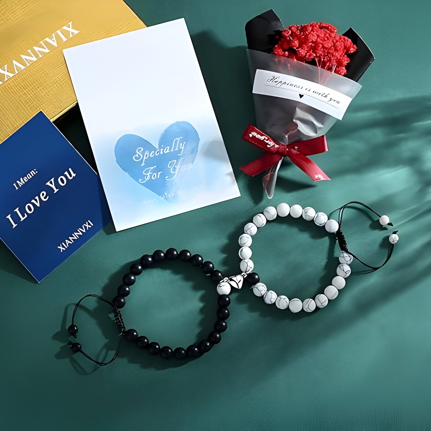 Duo de bracelets en agate noire et turquoise blanche avec cœur aimanté, présentés avec coffrets et bouquet rouge.