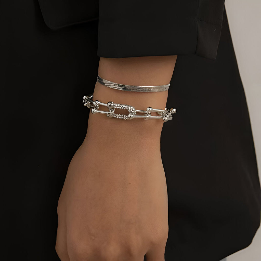 Duo de bracelets mousqueton en acier inoxydable argenté au poignet féminin, style moderne et épuré.