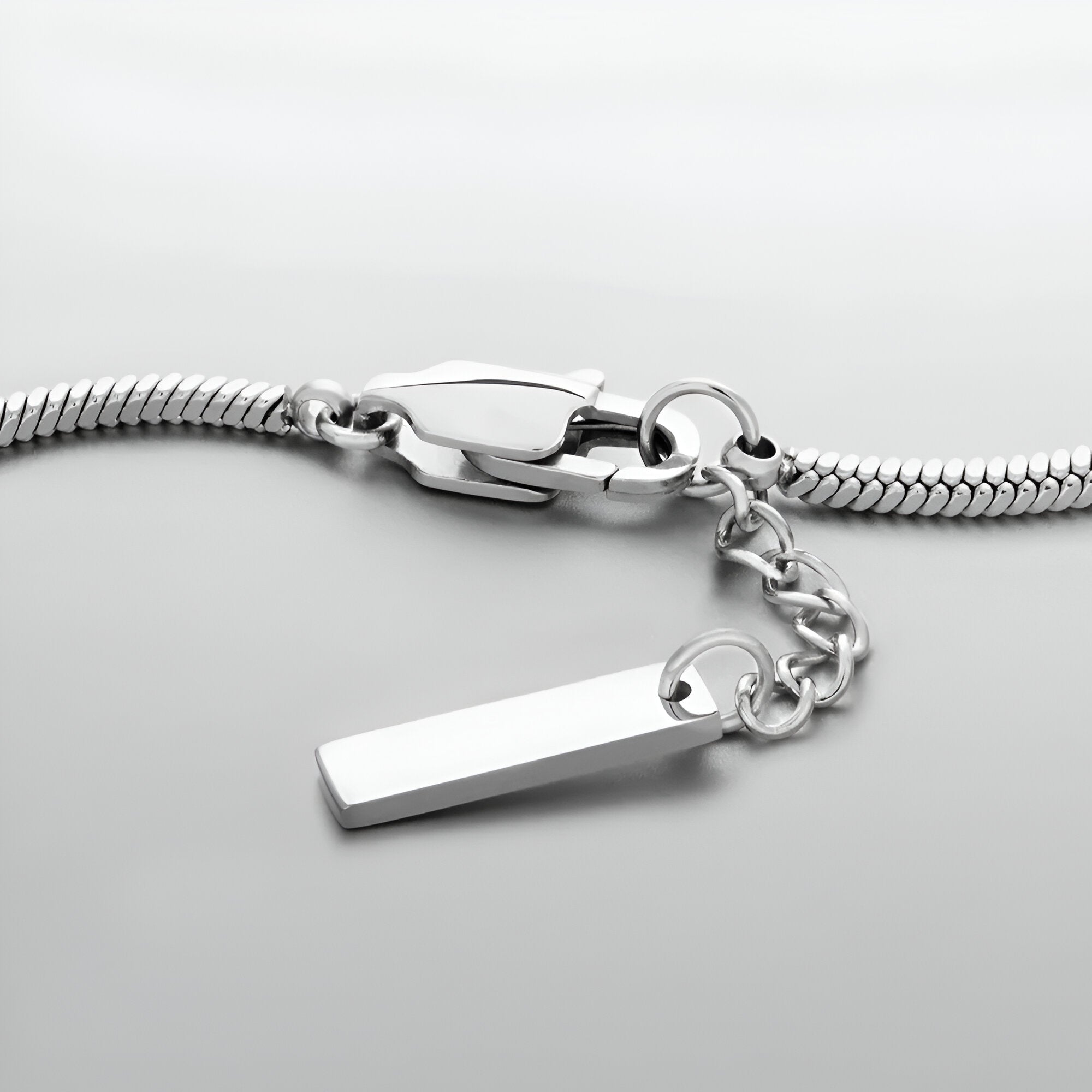 Bracelet homme en acier inoxydable, jonc maille serpent argenté avec chaîne de réglage et plaque rectangulaire lisse.