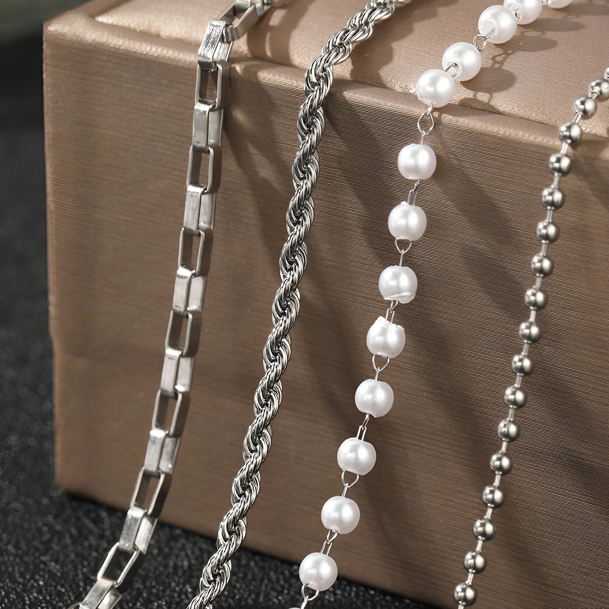 Ensemble de 4 bracelets en acier inoxydable argenté avec maillons carrés, torsadé, perles blanches et billes lisses.
