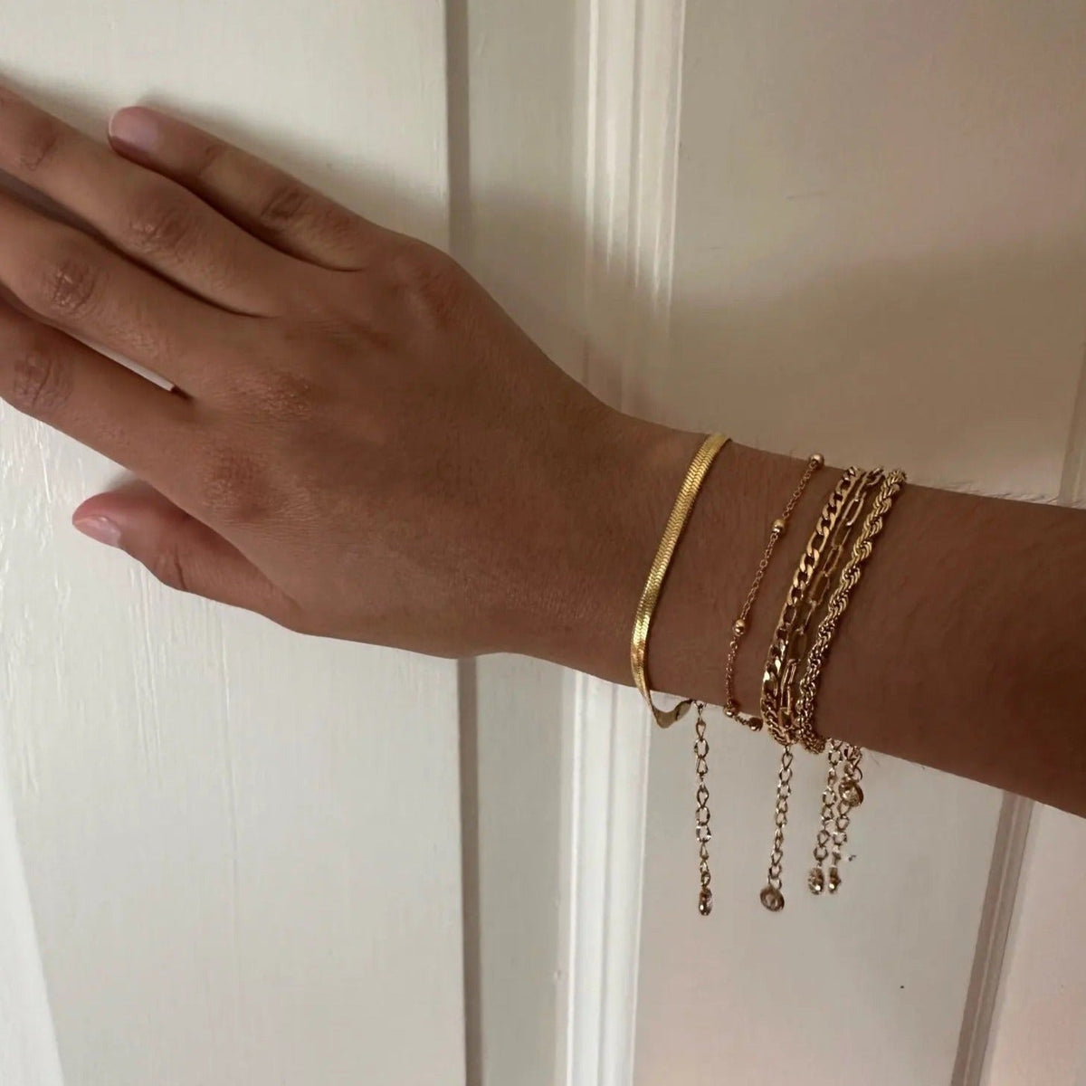 Ensemble de 5 bracelets en acier inoxydable doré, styles variés avec chaînes fines et lisses.