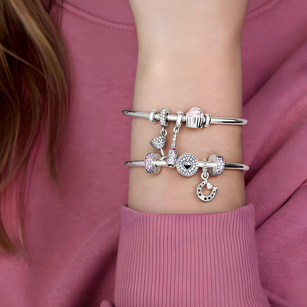 Bracelets argentés fins avec espaceurs et breloques éclatantes sur poignet féminin.