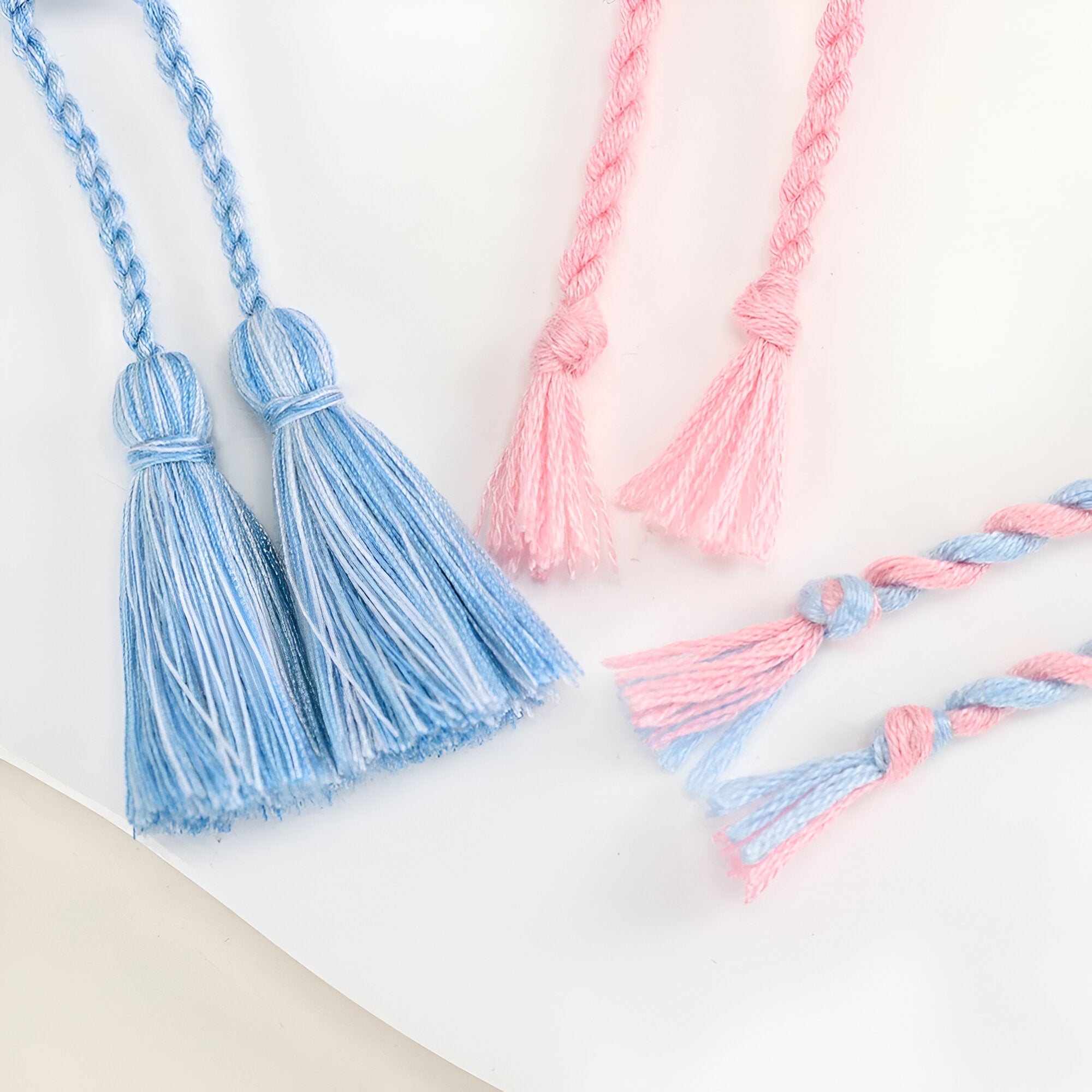 Trio de bracelets en coton tissé bleu et rose avec motifs papillons et pompons délicats.