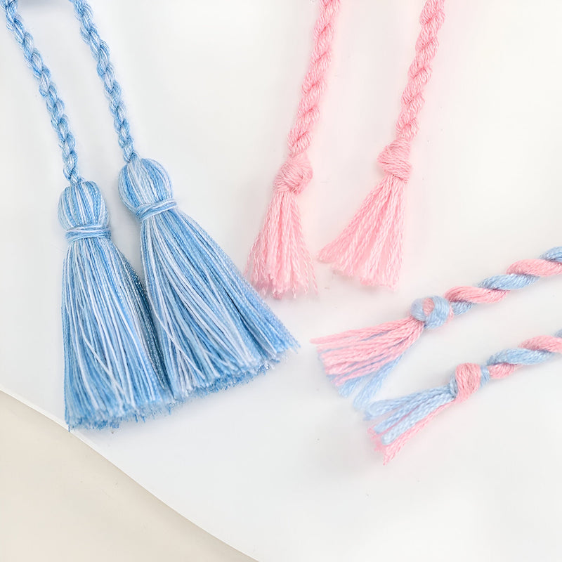 Trio de bracelets en coton tissé bleu et rose avec motifs papillons et pompons délicats.