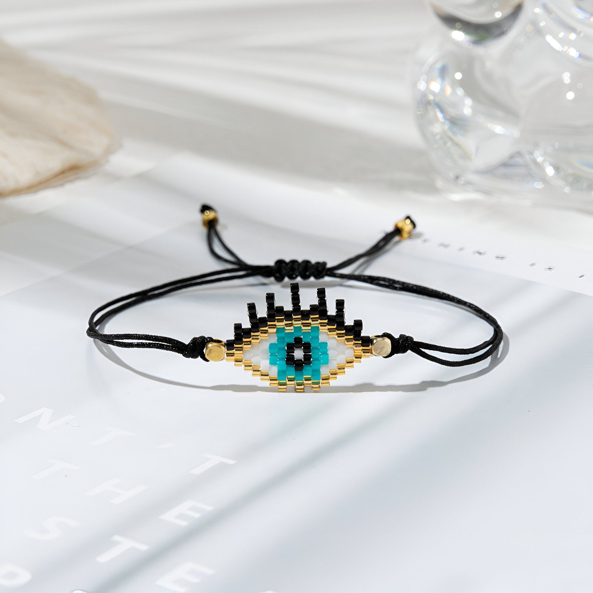 Trio de bracelets noirs en perles japonaises avec motif œil de protection bleu et beige.