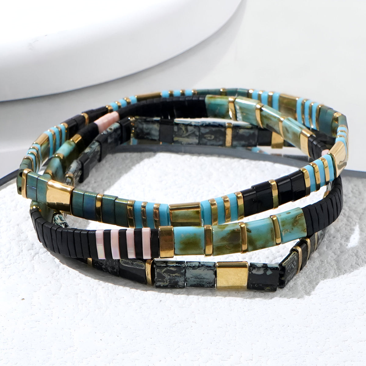 Trio de bracelets en perles multicolores japonaises avec accents dorés et design géométrique.
