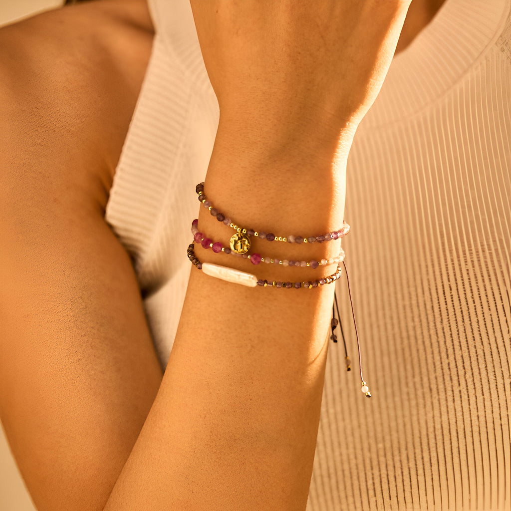 Trio de bracelets violet en pierre naturelle avec breloques dorées et fermoirs ajustables.