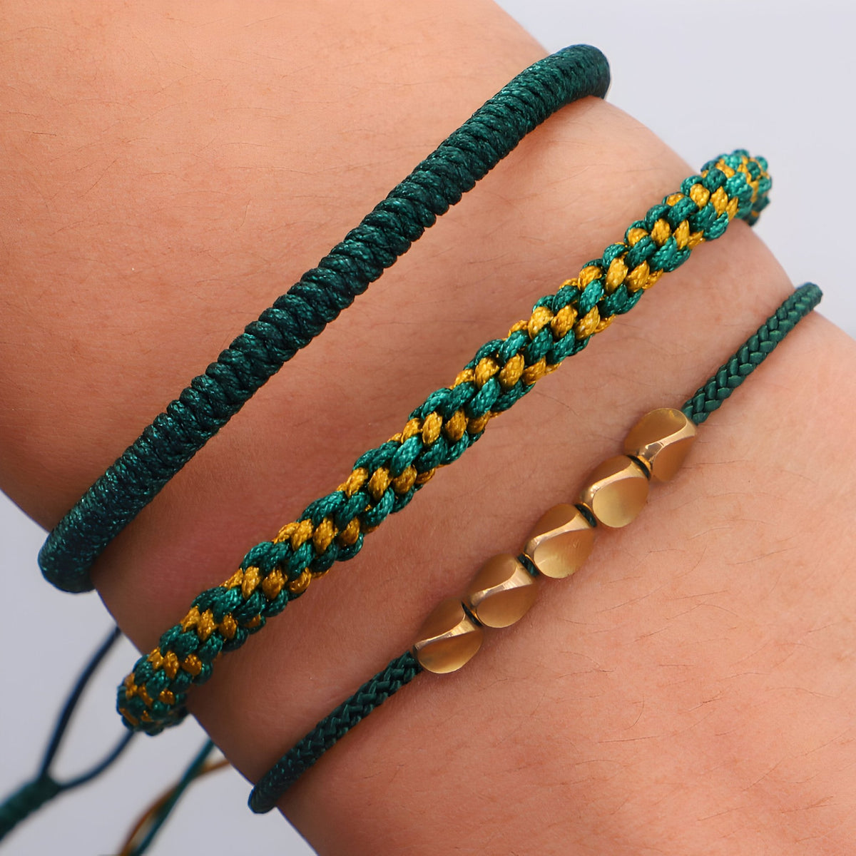 Trio de bracelets tibétains verts en corde tressée et perles de cuivre hexagonales.