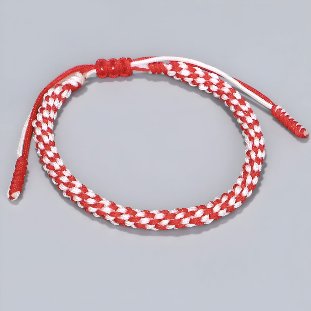 Bracelet tibétain en corde rouge et blanche tressée avec fermeture ajustable en cuivre.