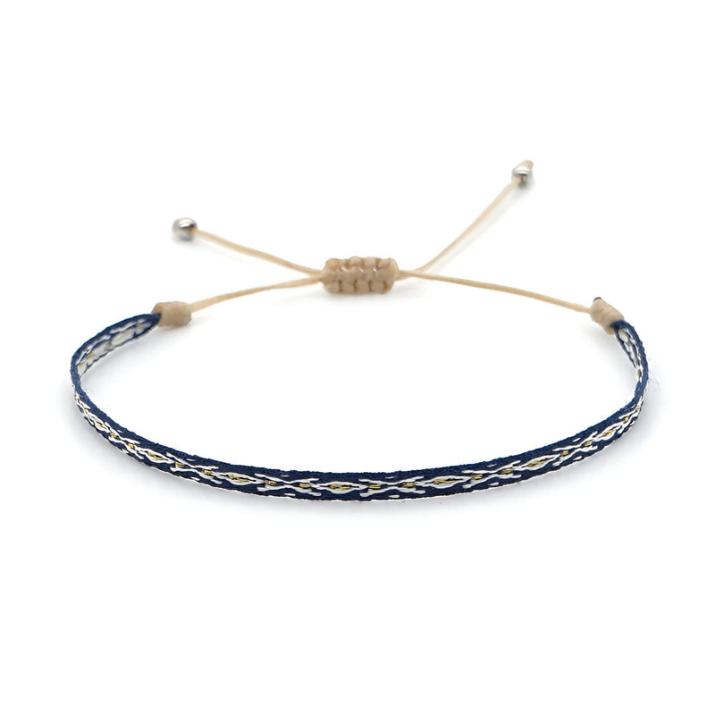 Bracelet tibétain bleu en coton tressé avec motifs argentés et fermeture ajustable beige.