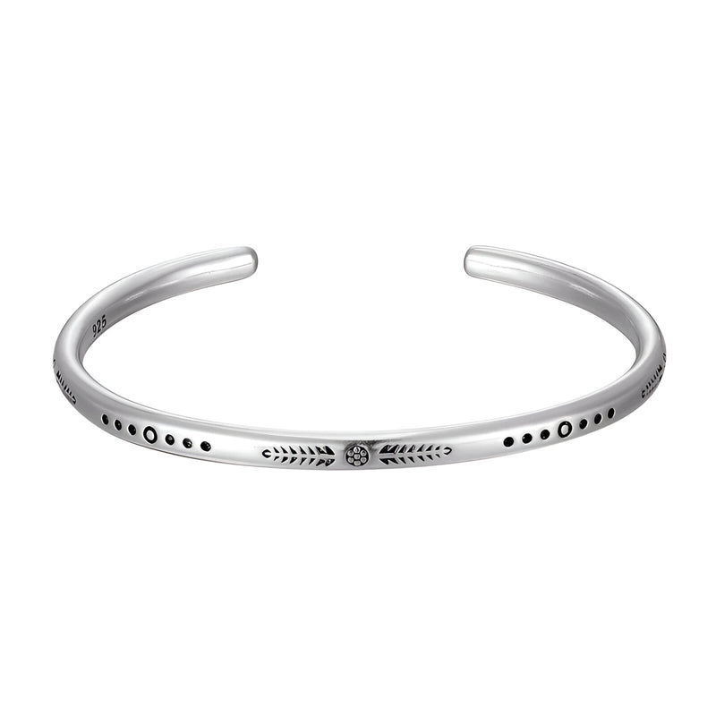 Bracelet jonc en argent avec motif gravé et détails en pointillés noirs, style minimaliste.