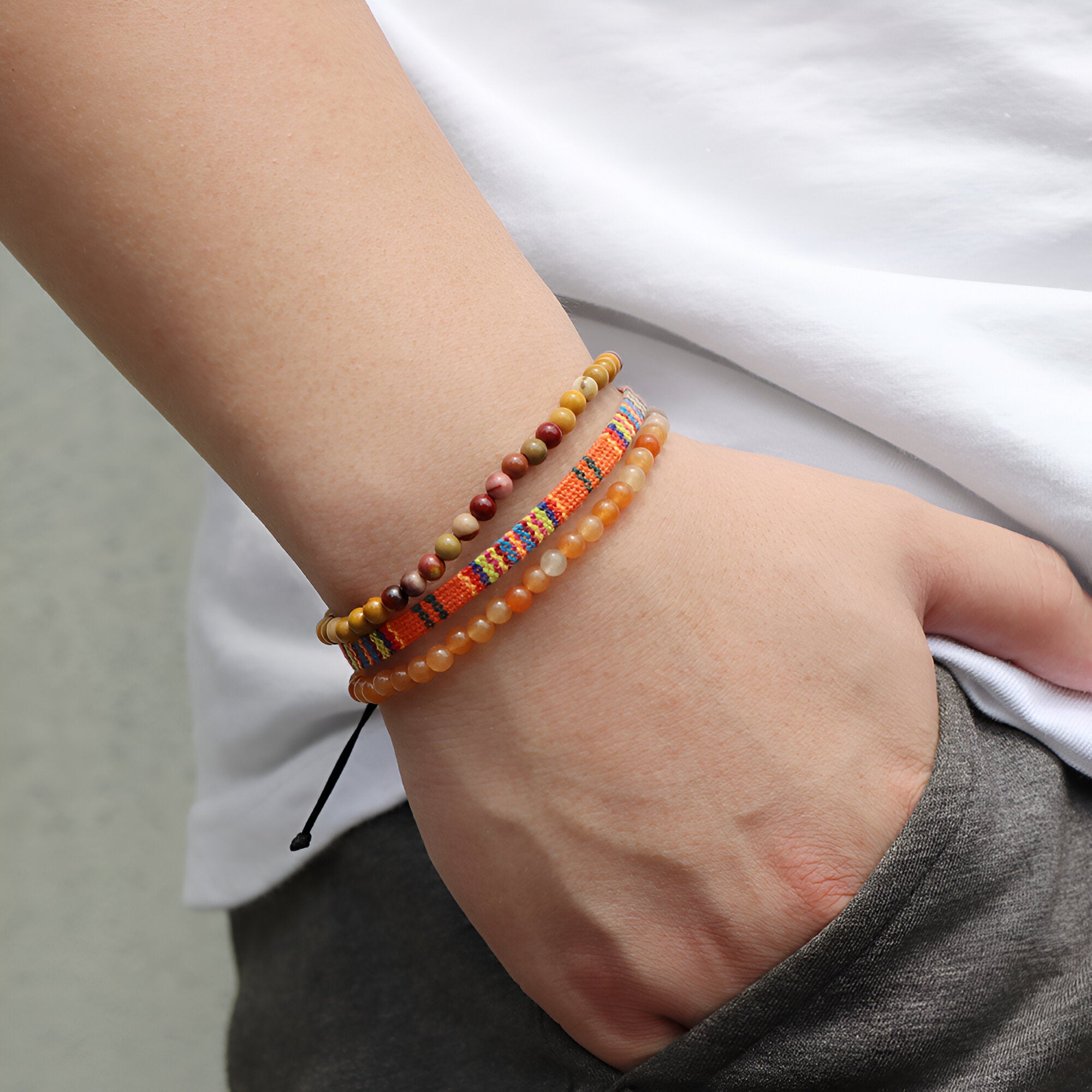 Trio de bracelets tibétains en jaspe rouge et orange avec perles et cordon réglable porté au poignet.