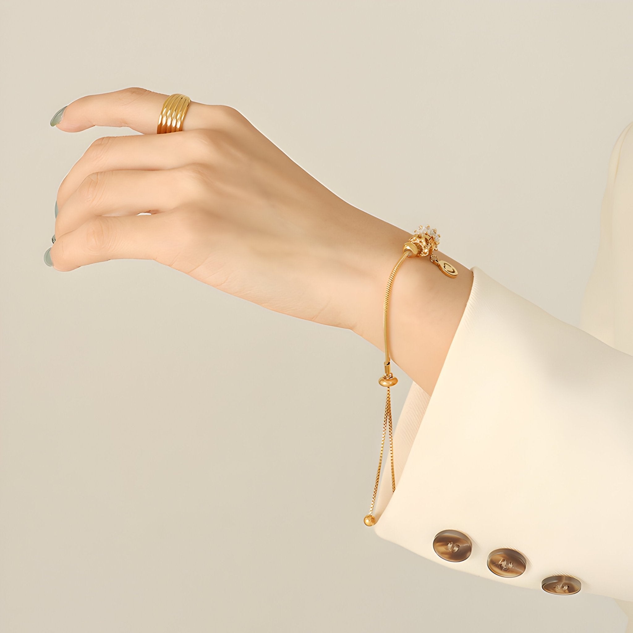Bracelet ajustable en titane doré avec motif cœur et zircons, porté au poignet femme.
