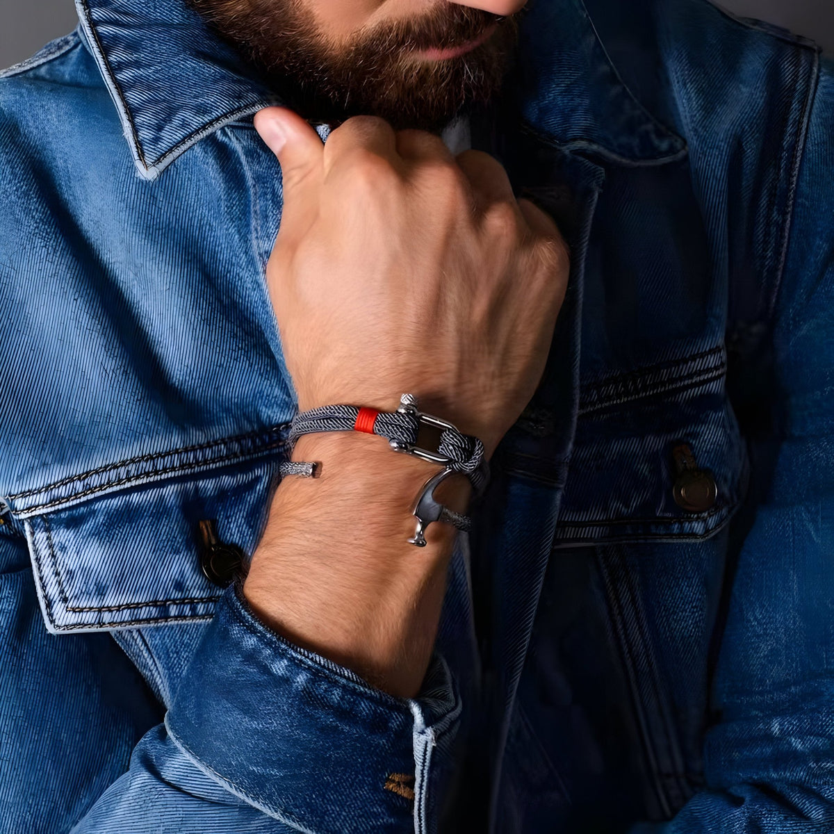Bracelet cordon orange avec mousqueton argenté porté au poignet homme, style décontracté.