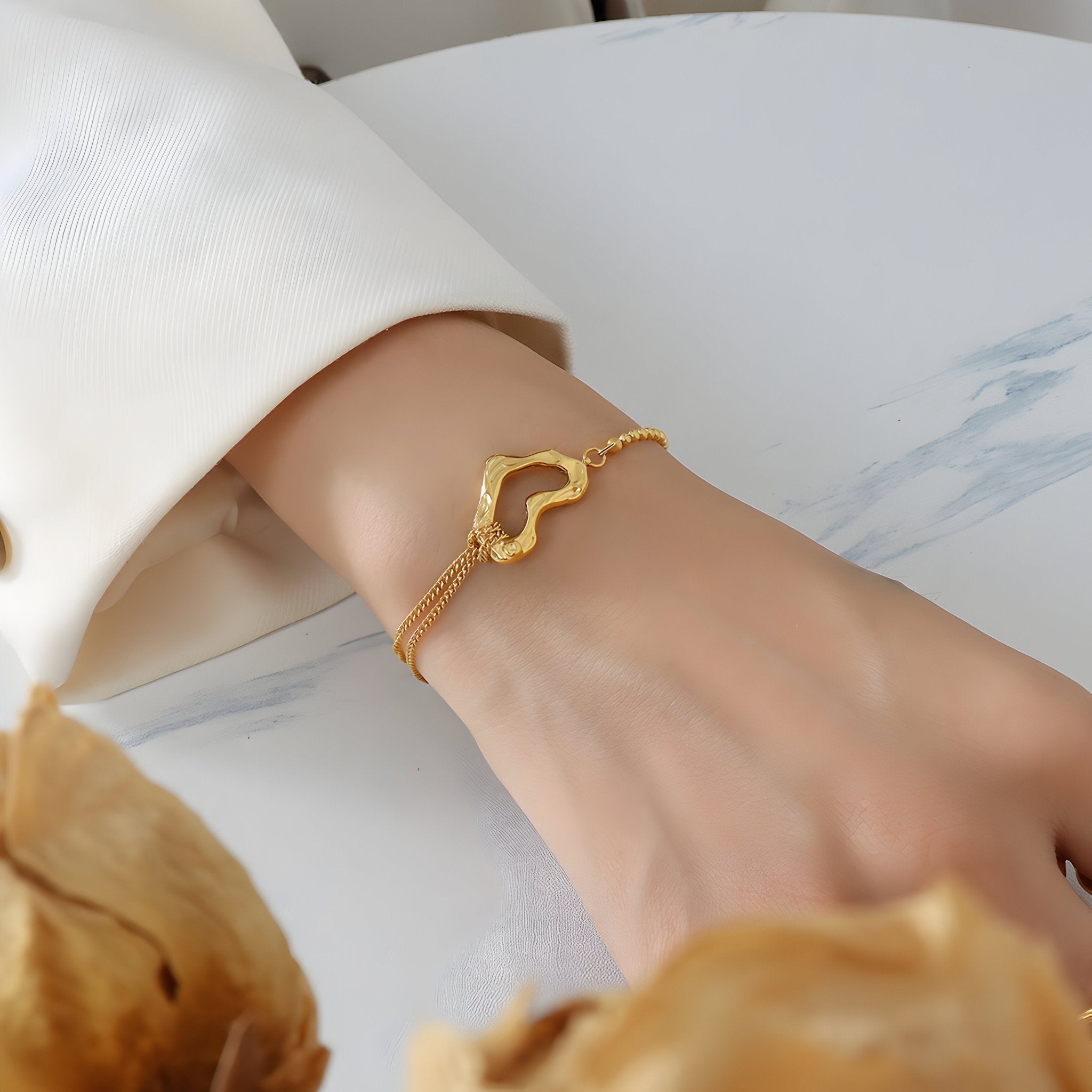 Bracelet délicat en titane plaqué or 18 carats avec motif cœur sur chaîne fine portée au poignet.