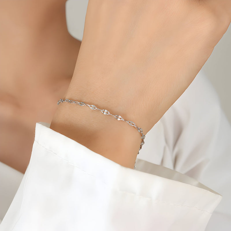 Bracelet fin en titane plaqué argent avec maillons délicats sur poignet féminin.