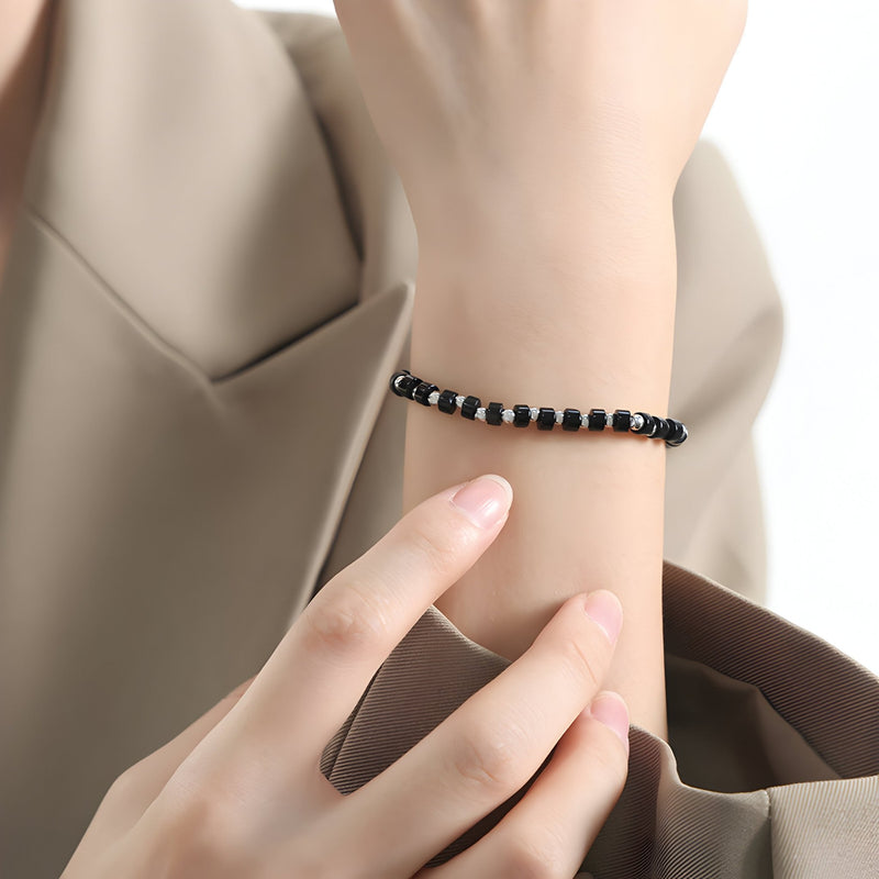 Bracelet fin en acier inoxydable noir avec petites perles rondes, style minimaliste.