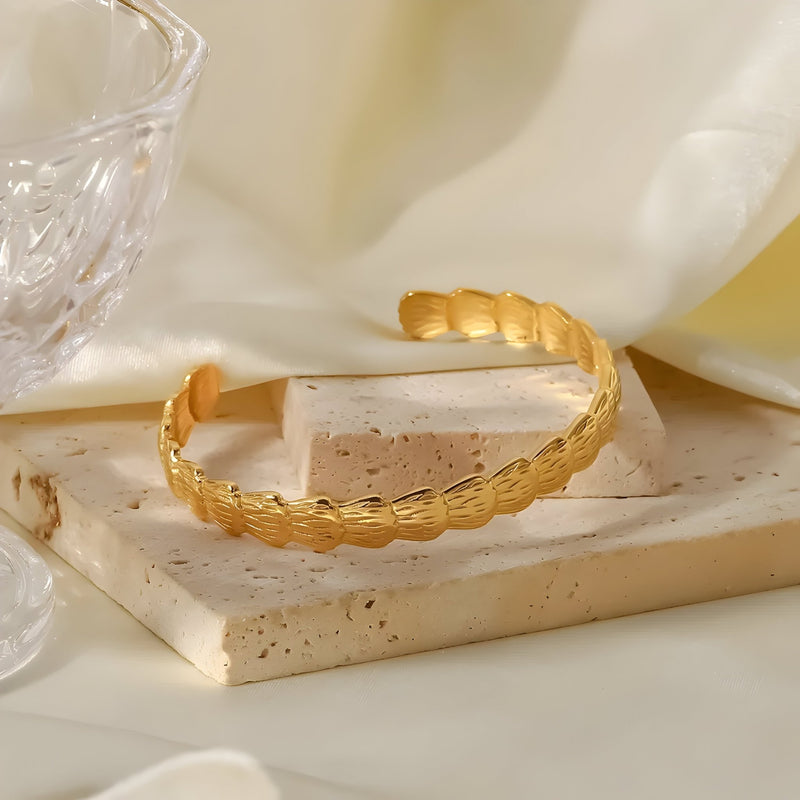 Bracelet jonc ouvert en acier inoxydable plaqué or avec motif torsadé élégant.