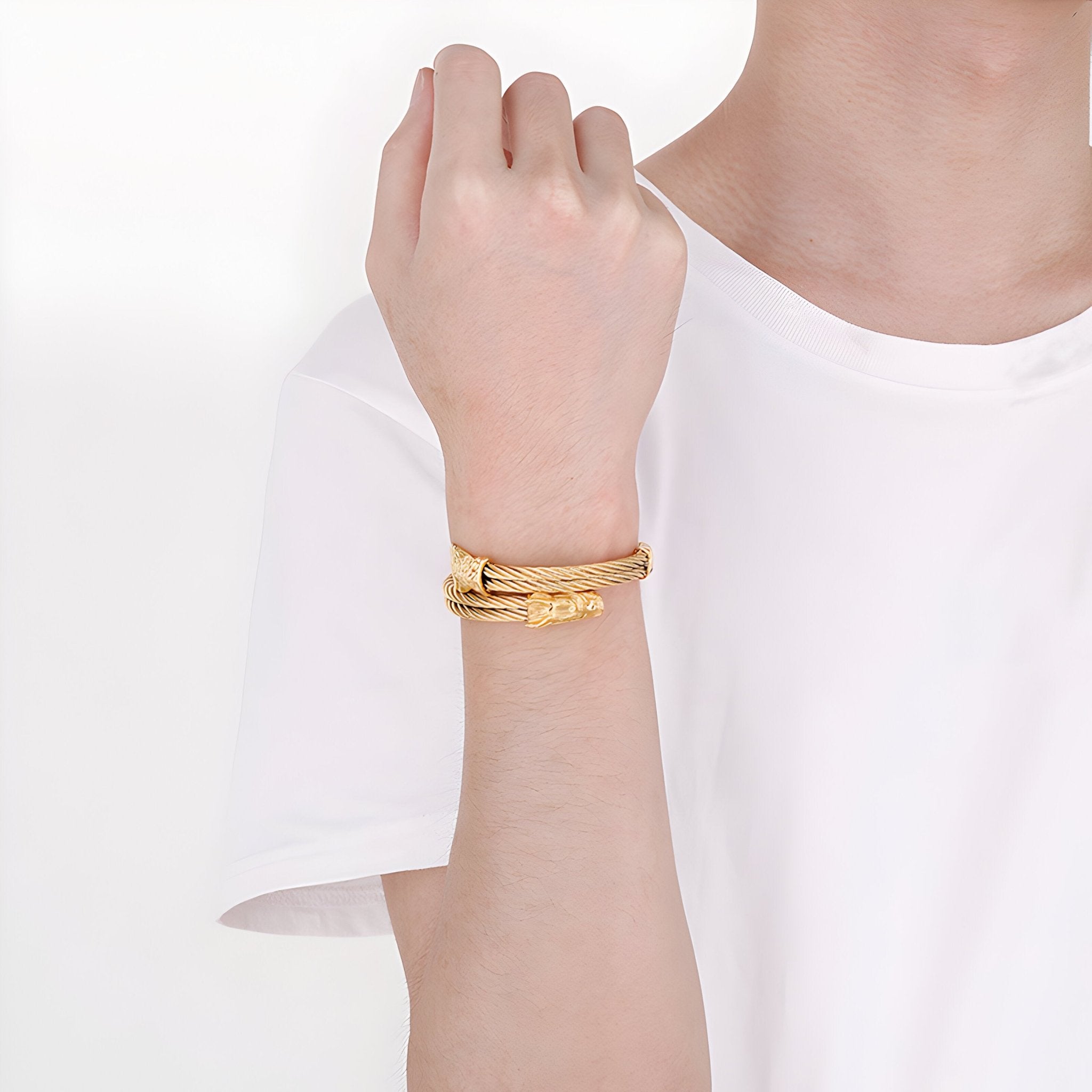 Bracelet jonc homme en acier inoxydable doré avec motif dragon gravé porté au poignet.