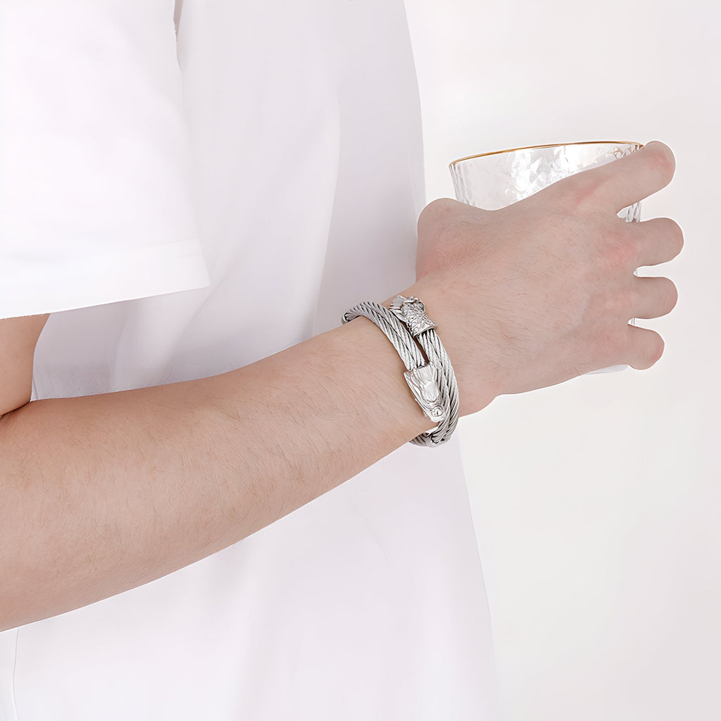 Bracelet jonc en acier inoxydable argenté avec motif dragon porté au poignet homme.