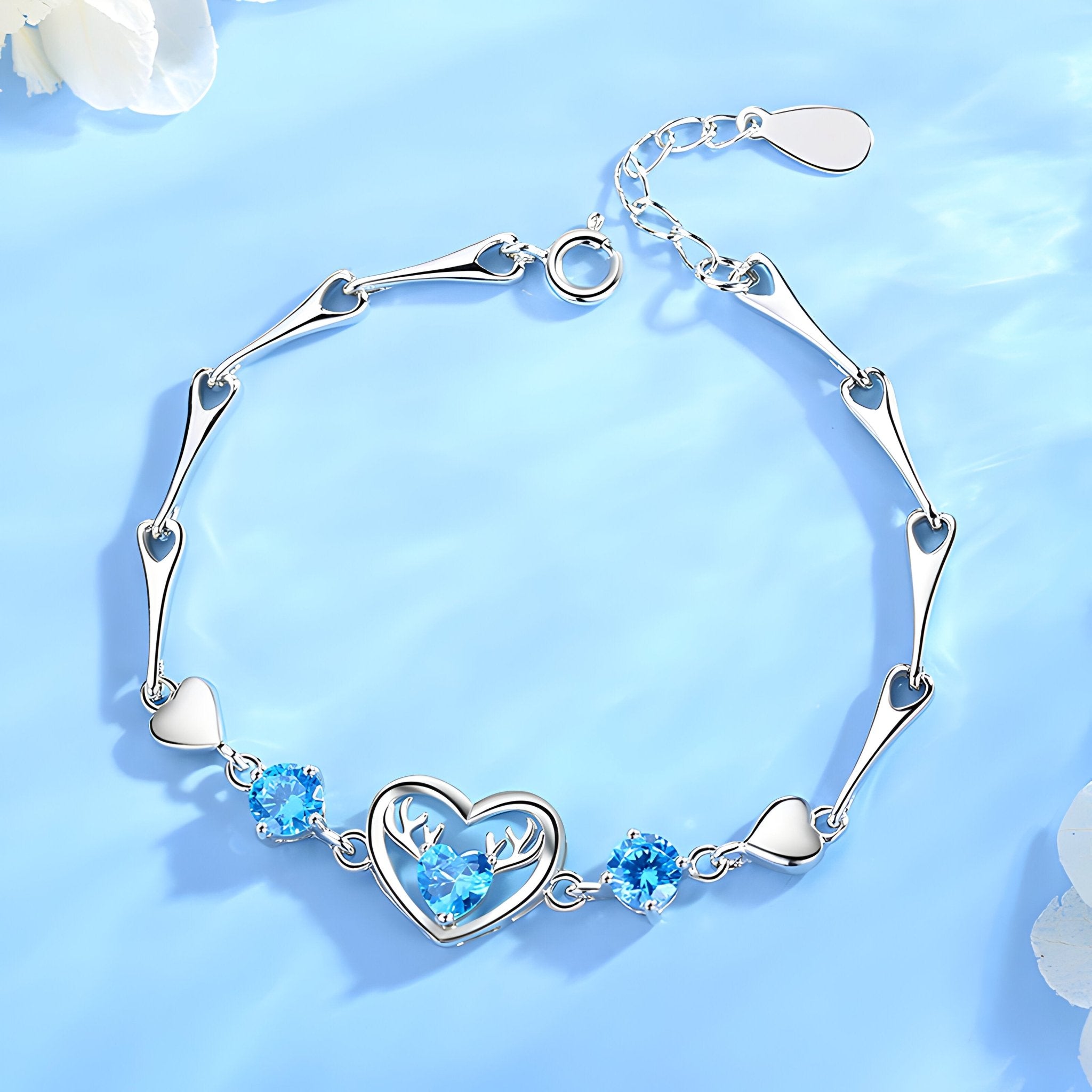 Bracelet en argent avec charms cœur et cristaux bleus, design délicat et élégant pour femme.