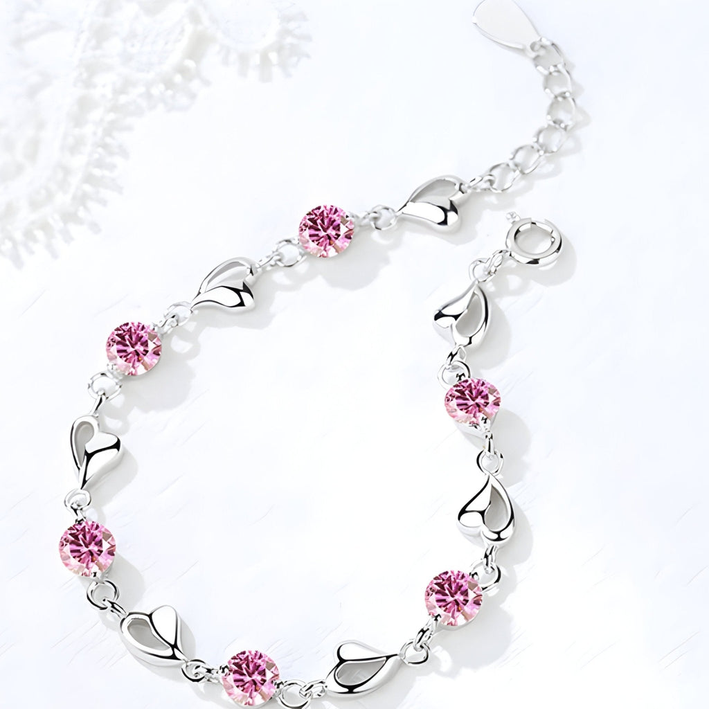 Bracelet en argent avec maillons en forme de cœur et pierres roses serties.