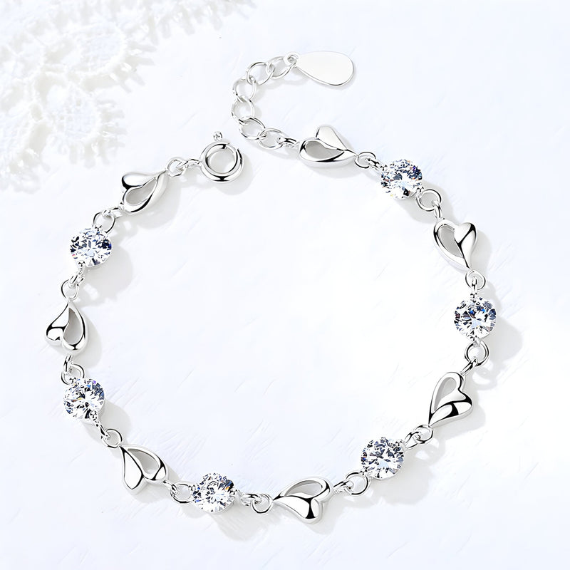 Bracelet en argent pur pour femme avec maillons en forme de cœur et pierres bleues brillantes.