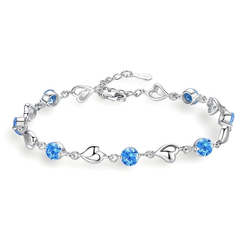 Bracelet en argent avec maillons en forme de cœur et pierres bleues scintillantes.