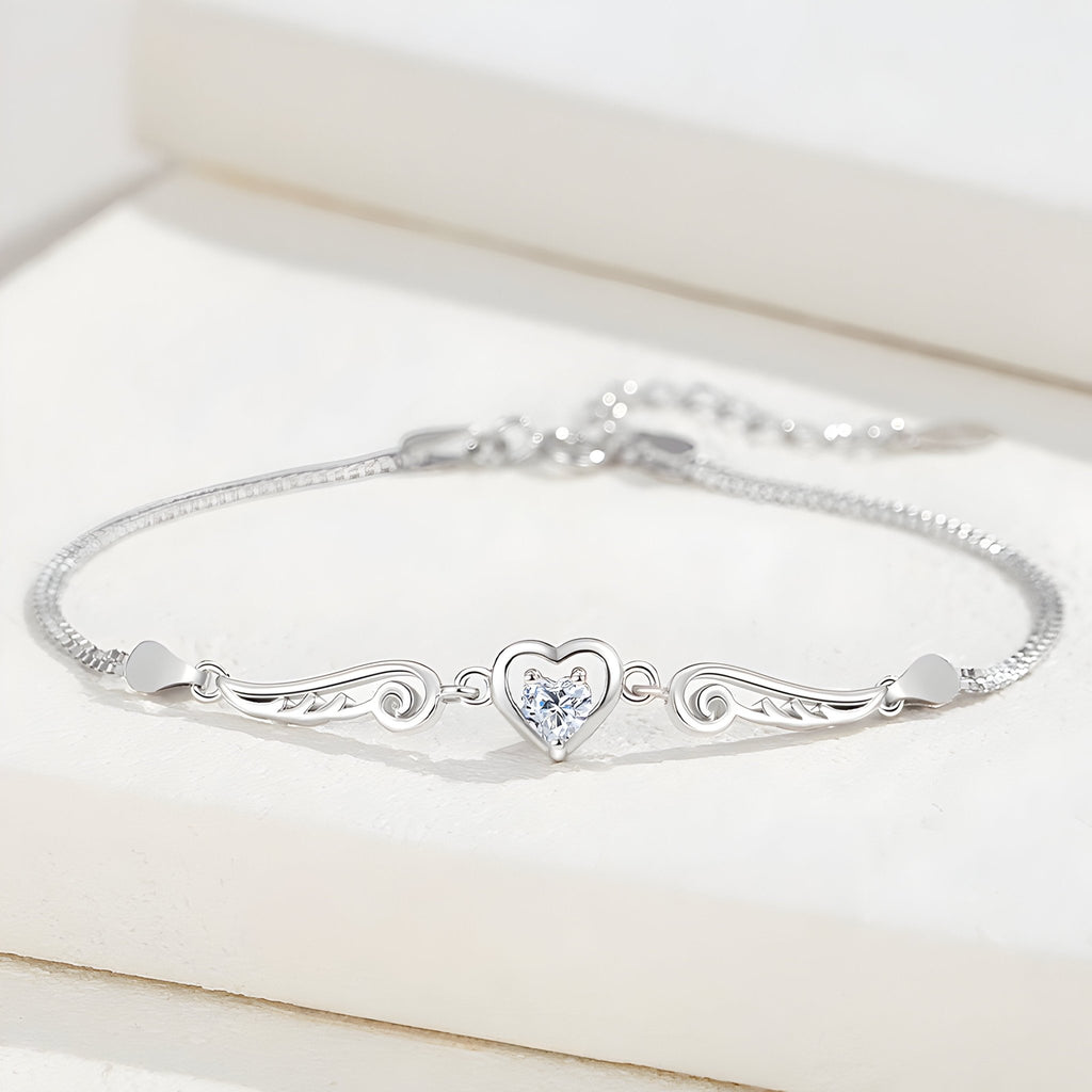 Bracelet fin en argent sterling avec un cœur central orné d’un cristal, ailes d’ange délicates de chaque côté.