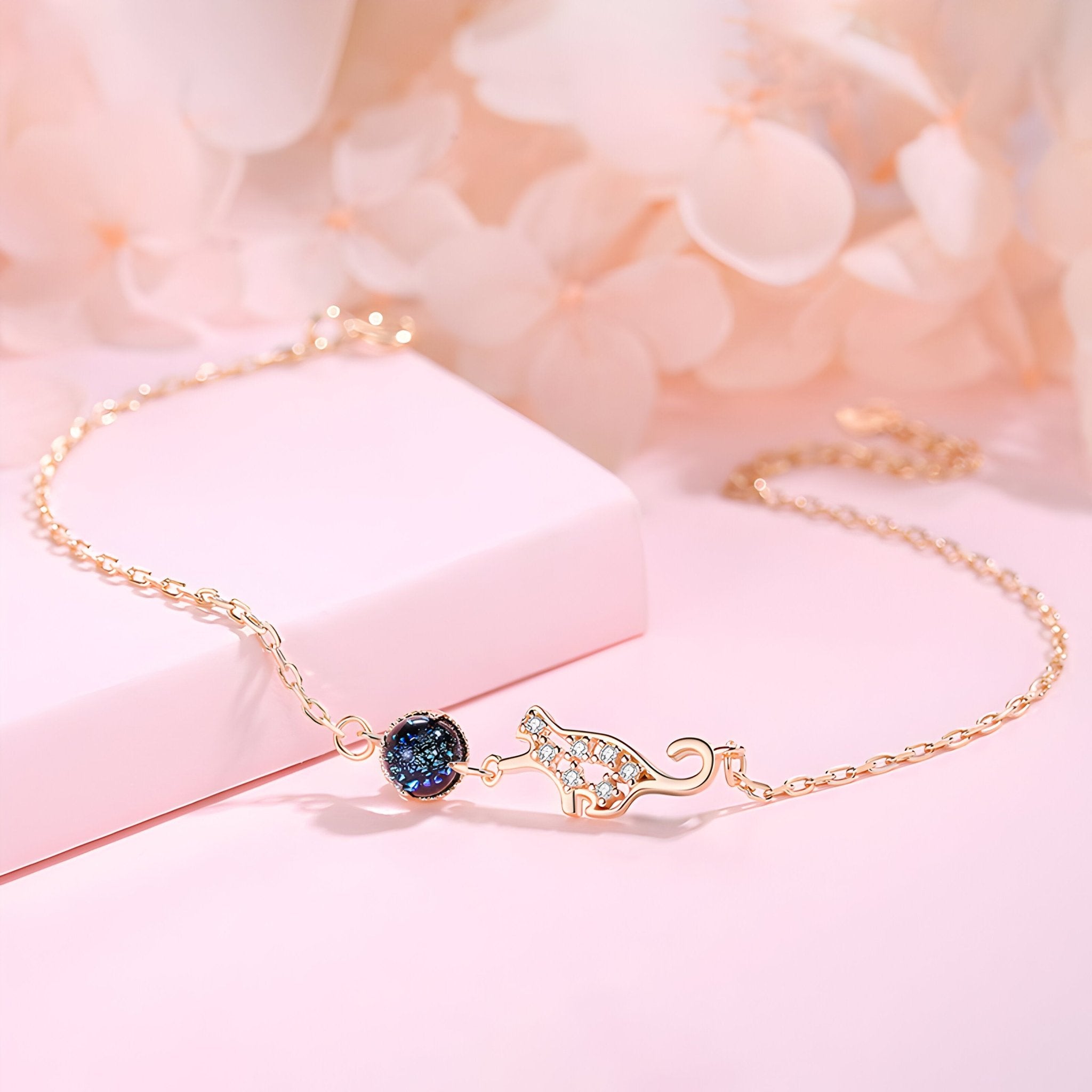 Bracelet en argent sterling avec chaîne fine et charm chat ajouré orné d'une pierre bleue brillante.