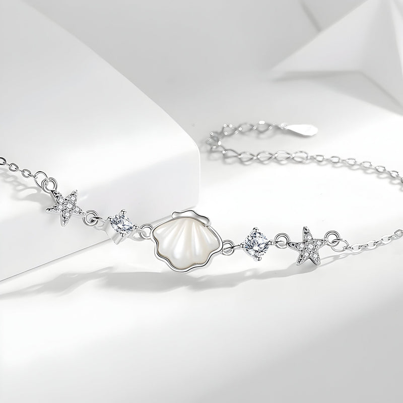 Bracelet en argent sterling avec pendentifs coquillage nacré et étoiles de mer, détails cristaux transparents.