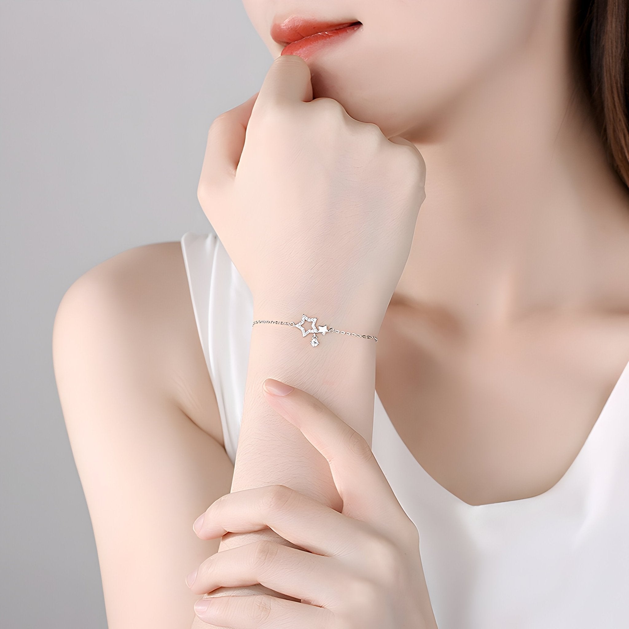 Bracelet fin en argent sterling avec deux étoiles entrelacées porté au poignet féminin.