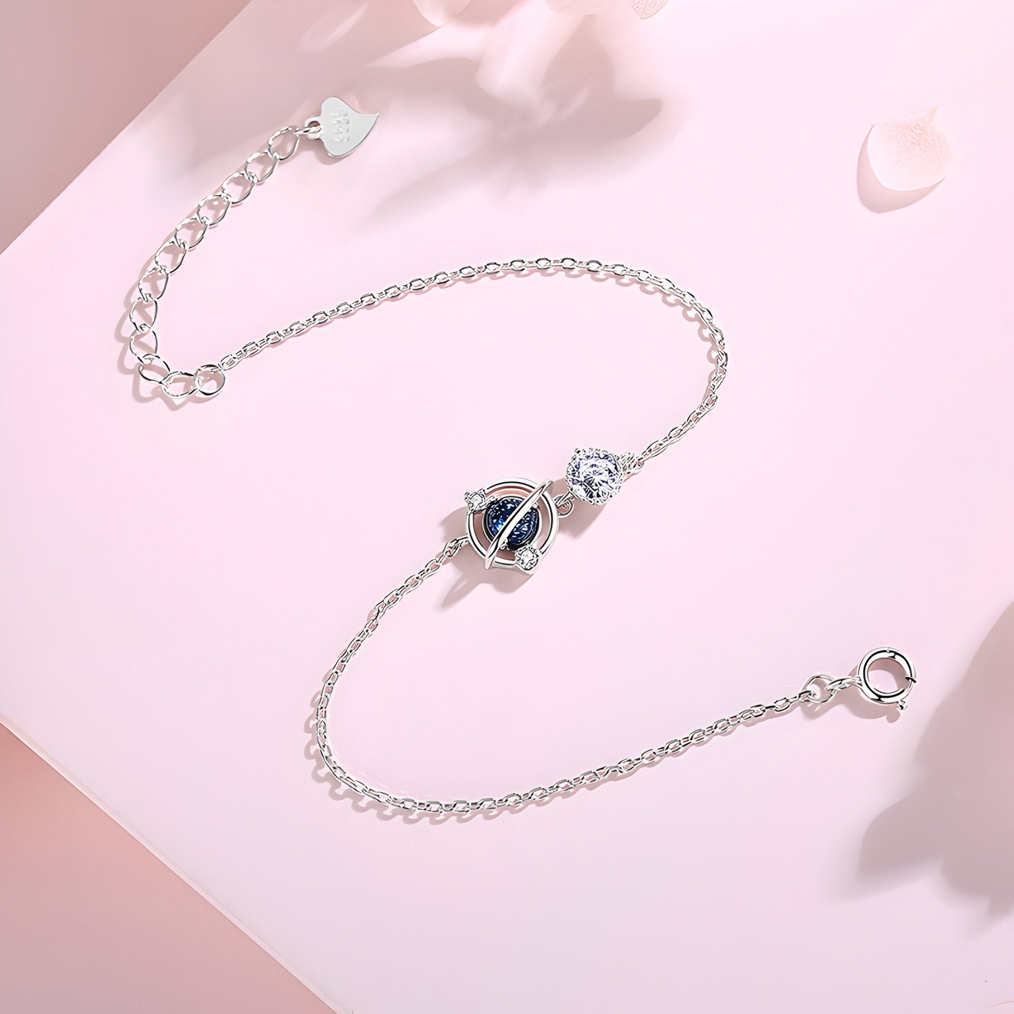Bracelet fin en argent sterling avec pendentif planète bleue et détail étoile scintillante.