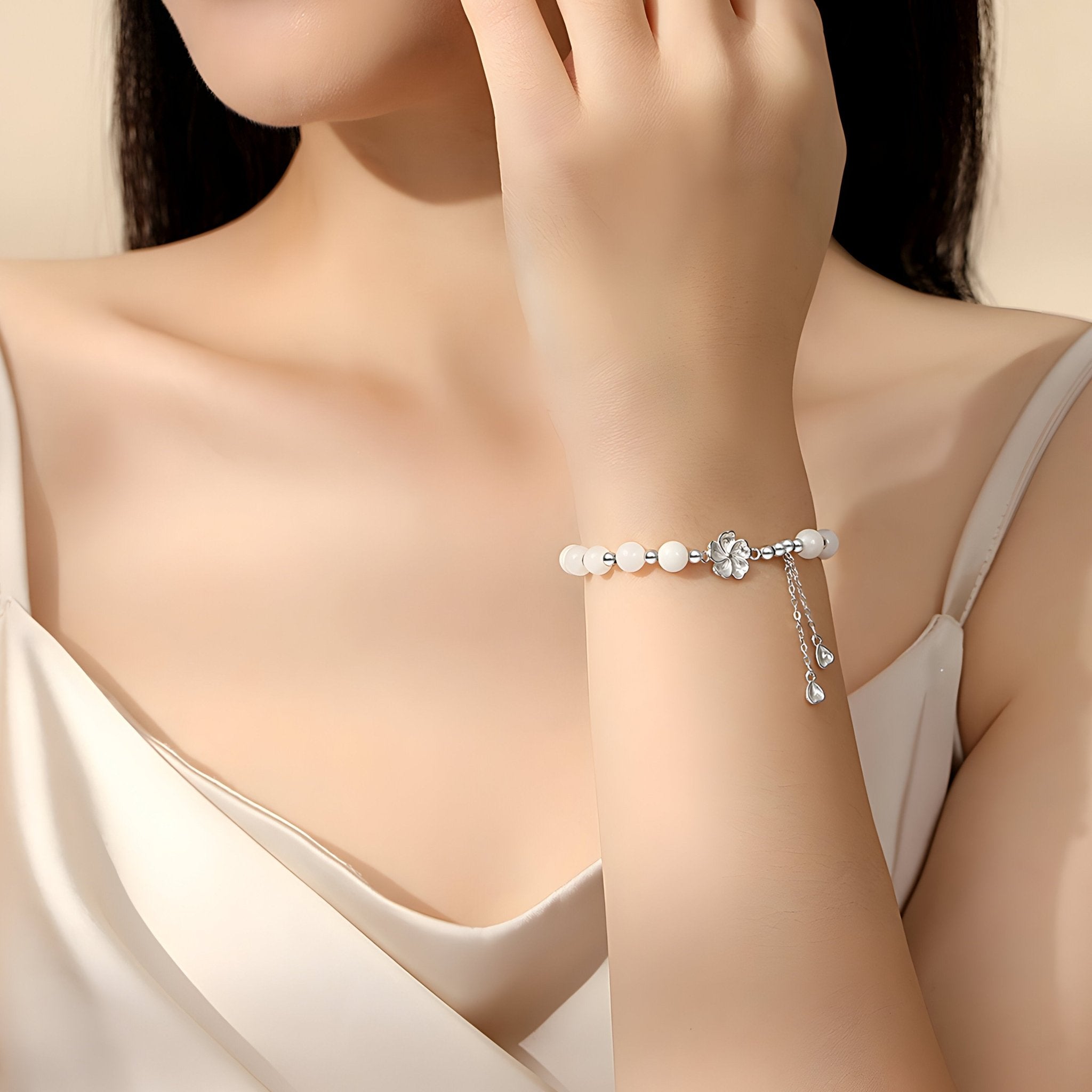 Bracelet en argent sterling avec perles blanches rondes et pendentif délicat porté au poignet féminin.