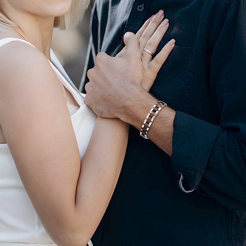 Bracelet en bois de noyer marron aux reflets éclatants porté sur poignet masculin avec chemise noire.