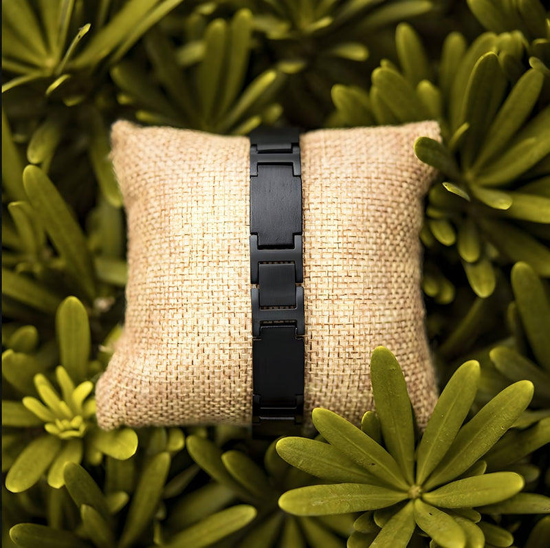 Bracelet homme en bois d'ébène noir mat, style contemporain, présenté sur coussin beige en toile de jute.