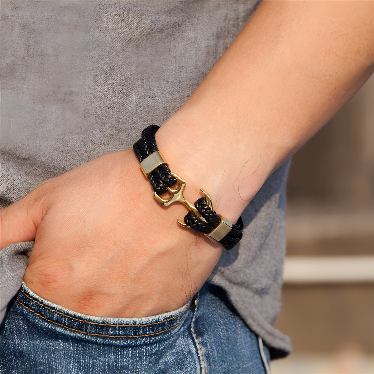 Bracelet en cuir noir avec motif ancre dorée, fermeture à boucle élégante.
