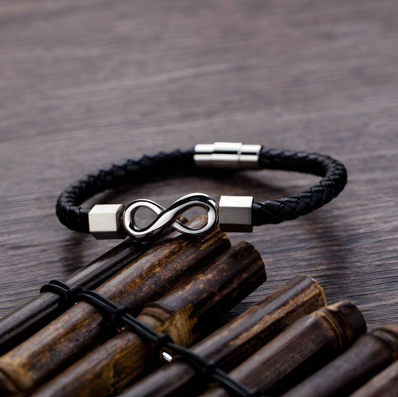 Bracelet en cuir noir tressé avec ornement infini en métal argenté, fermoir magnétique gris.