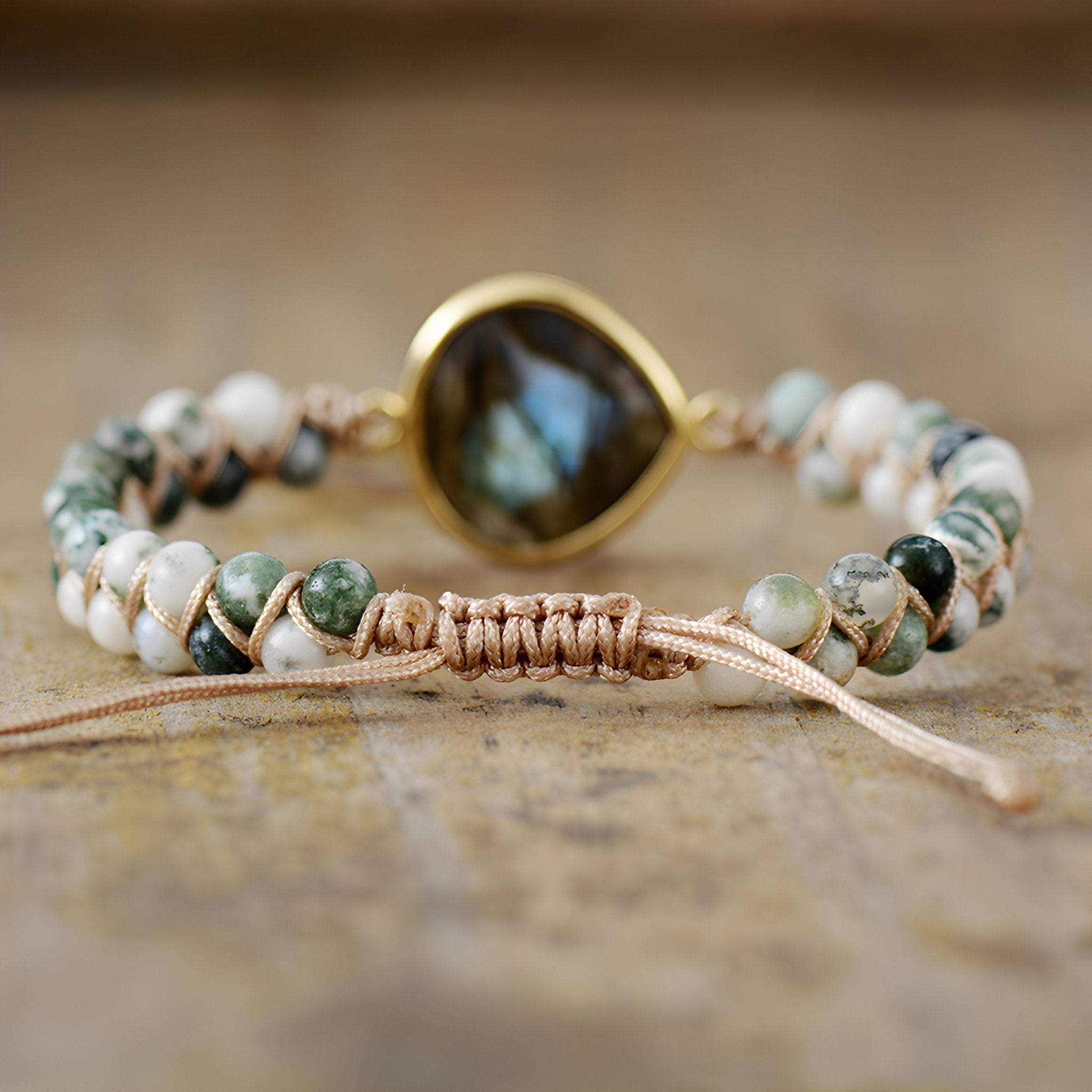 Bracelet femme pierres naturelles labradorite bleue centrale sertie or, perles blanches et vertes sur cordon beige tressé.