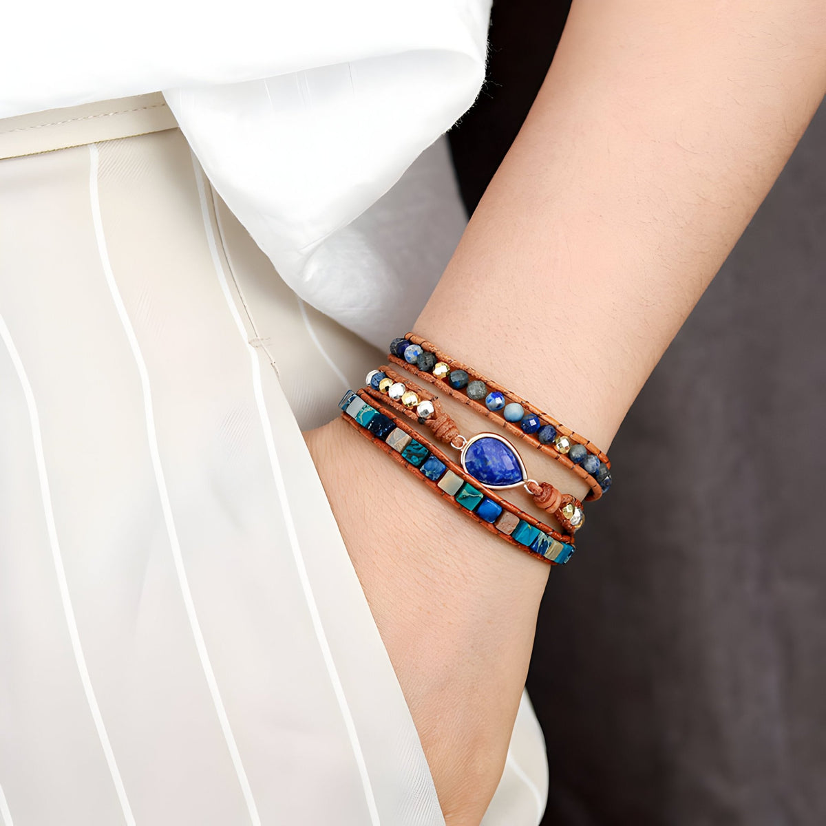 Bracelet multi-rangs en lapis lazuli bleu, pierres jaspe marron et perles turquoise, portée au poignet.