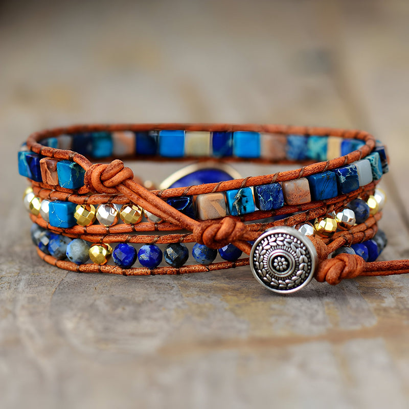 Bracelet multi-rangs en lapis lazuli, jaspe bleu, perles dorées, cuir marron et fermoir bouton argenté décoré.