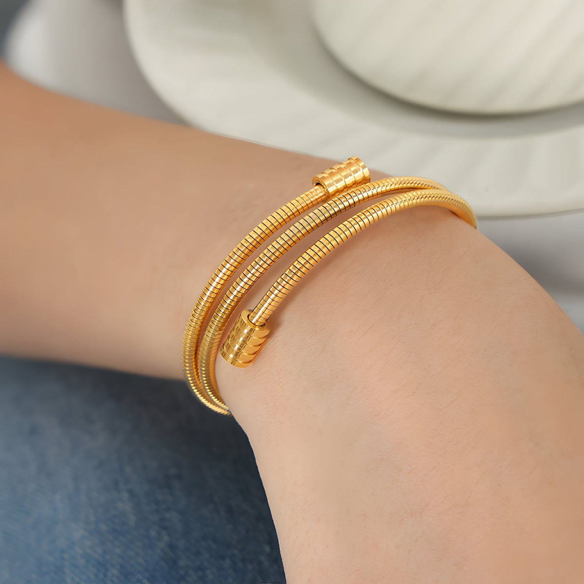 Bracelet joncs souples en maille serpent doré en titane, design élégant Grace, porté au poignet.