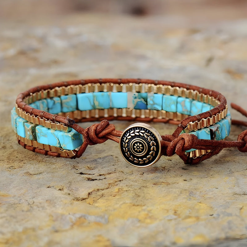 Bracelet multi-rangs en cuir marron avec pierres turquoise carrées et bouton métal rond gravé.