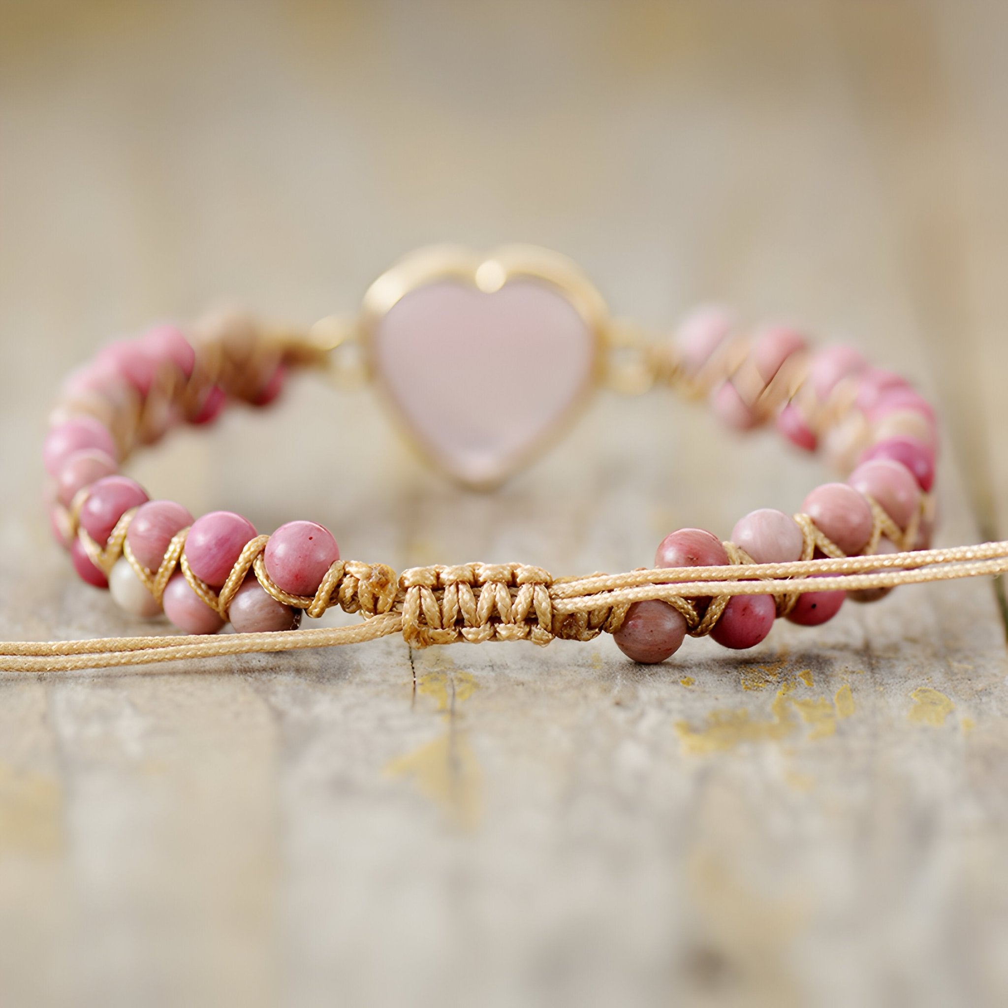 Bracelet en rhodonite rose avec pendentif cœur en quartz rose monté sur corde tressée beige.