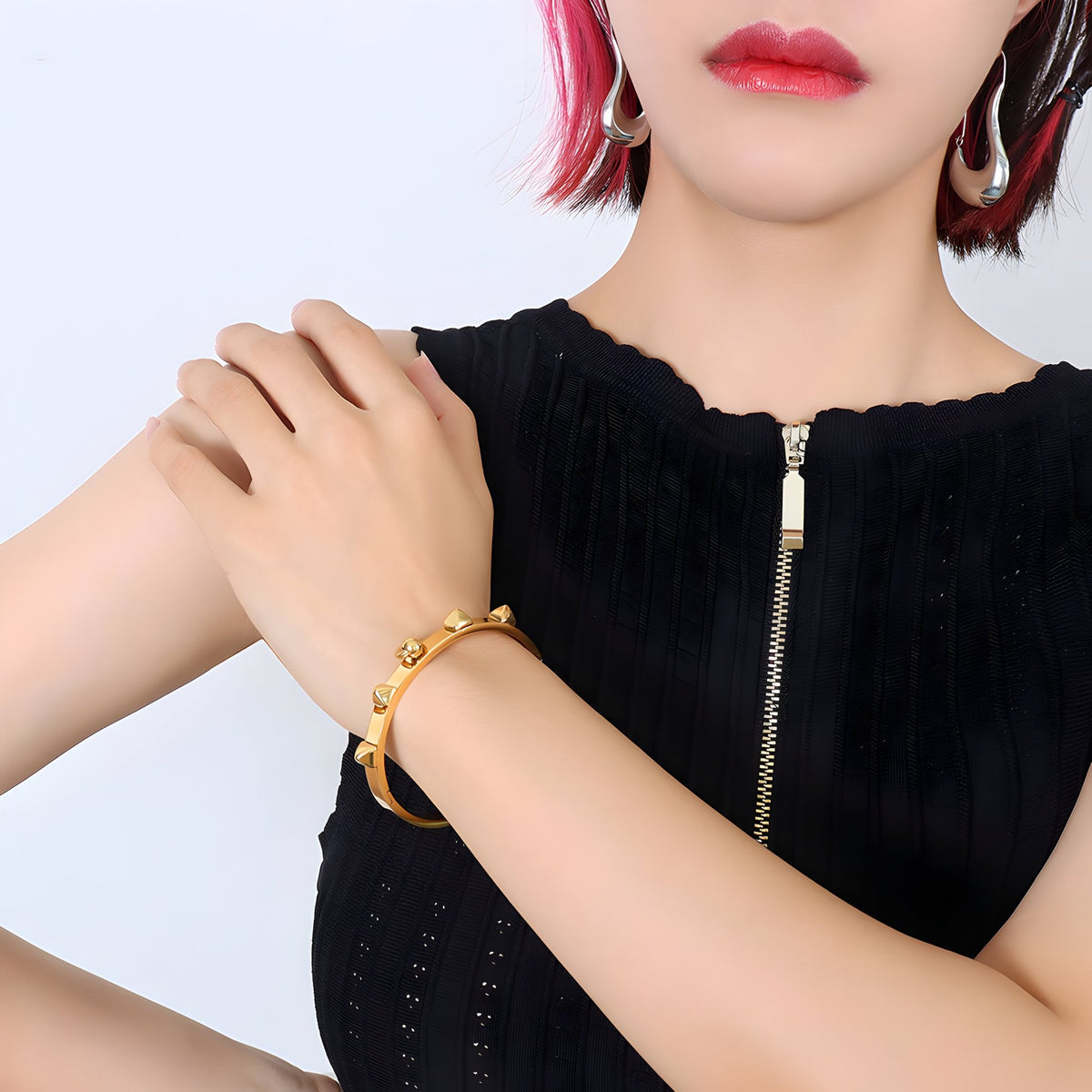 Bracelet en titane plaqué or 18 carats avec piques, style moderne et audacieux, porté au poignet.
